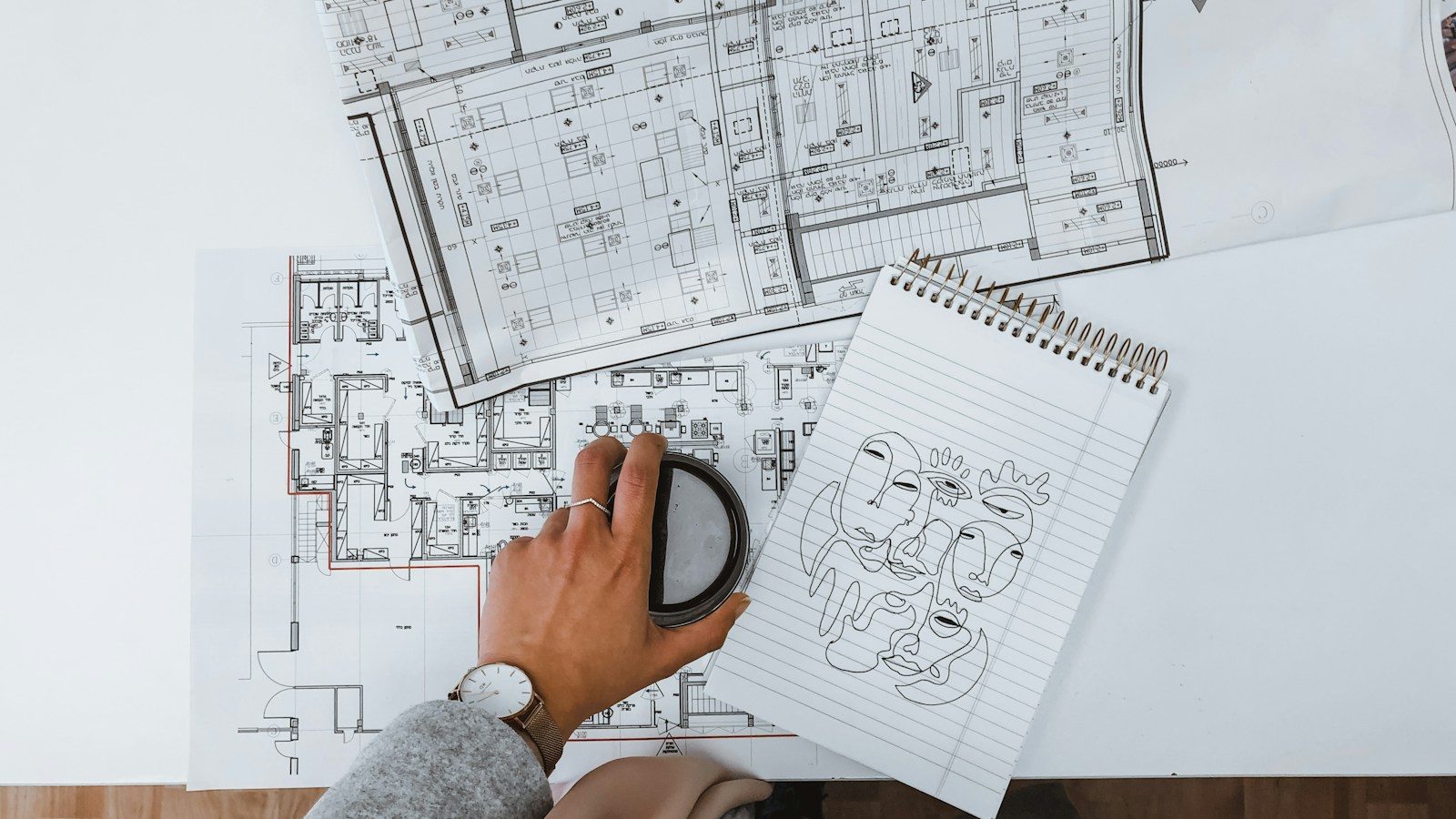 Bouwplannen en een notitieboekje met schetsen op een wit werkblad